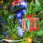 Close-up of a decorated Christmas tree with a plaid gift ornament and twinkling lights.